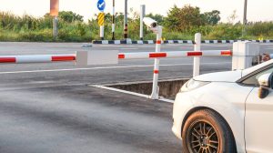 A white car parked at a barrier which has a camera to identify license plates